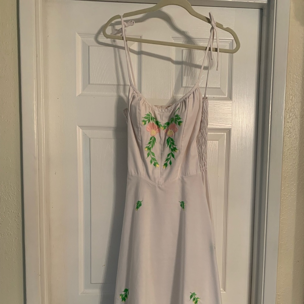 White dress with tie straps and embroidered flowers.